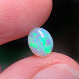 Opal stone held between fingers with a blurred background