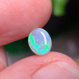 Opal stone held between fingers with a blurred background