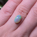 Opal stone on a person's finger with a blurred background