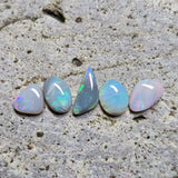 Five opal stones on a textured stone surface