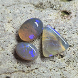 Three opal stones on a textured stone surface