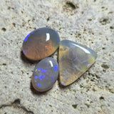 Three opal stones on a textured stone surface