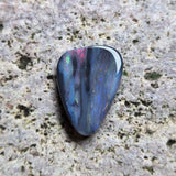 Multicolored opal stone on a textured beige surface