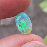 Opal stone held between fingers with a blurred natural background