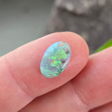 Opal stone held between fingers against a blurred background