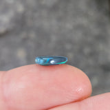 Small blue crystal held between fingers against a blurred background