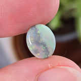 Opal stone held between fingers with a blurred background