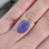 Opal stone held between fingers against a neutral background