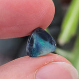 Hand holding an opal with a blurred natural background