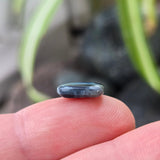 Small blue stone held between fingers with a blurred natural background