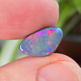 Opal stone held between fingers with a blurred natural background