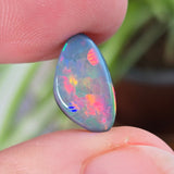 Opal stone held between fingers with a blurred natural background