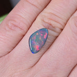 Opal stone held between fingers against a skin background