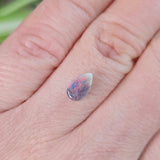 Small opal stone held between fingers against a blurred background