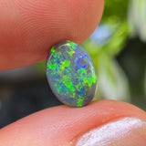 Opal stone held between fingers with a blurred natural background