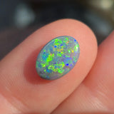 Opal stone held between fingers with a blurred background