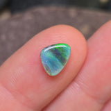 Opal stone held between fingers against a blurred background