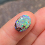 Opal stone held between fingers against a blurred background