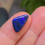 Blue opal stone held between fingers with a blurred background