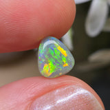 Opal stone held between fingers with a blurred natural background