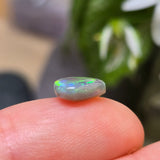 Opal stone held between fingers with a blurred background