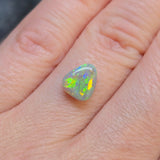 Opal stone held between fingers on a light skin background