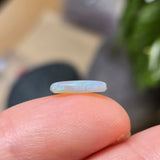 Opal stone held between fingers with a blurred background