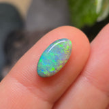 Opal stone held between fingers with a blurred natural background