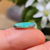 Opal stone held between fingers with a blurred floral background