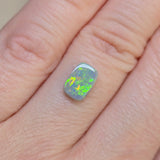 Opal stone held between fingers on a light skin background