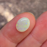Opal stone held between fingers against a blurred background