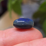 Blue stone held between fingers with a blurred natural background