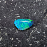 Blue-green gemstone on a dark gray surface