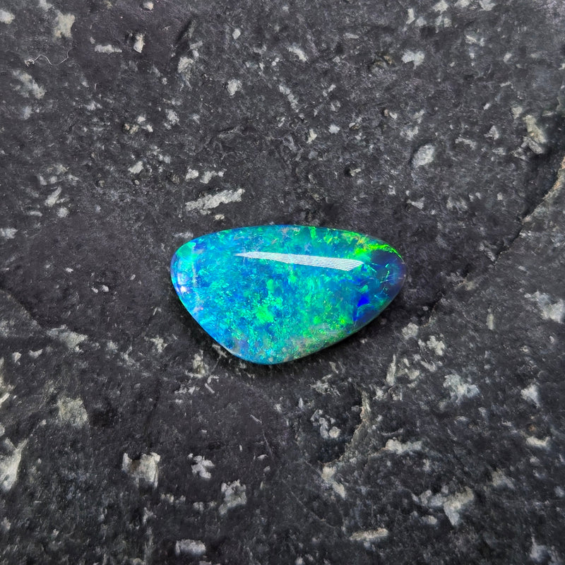 Blue-green gemstone on a dark gray surface