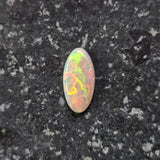 Multicolored opal stone on a dark textured surface
