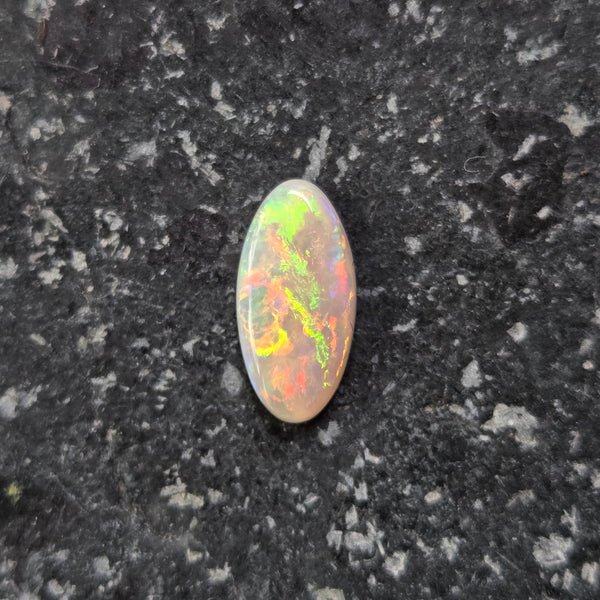 Multicolored opal stone on a dark textured surface