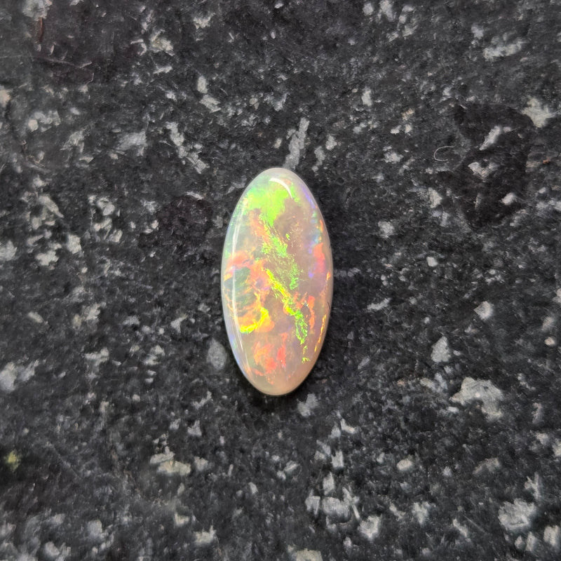 Multicolored opal stone on a dark textured surface