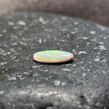 Small oval opal stone on a dark textured surface