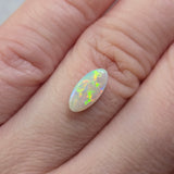 Opal stone held on finger against a neutral background