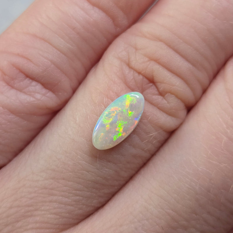 Opal stone held on finger against a neutral background