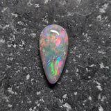 Multicolored opal stone on a dark textured surface