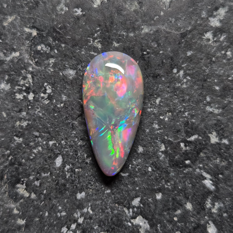 Multicolored opal stone on a dark textured surface