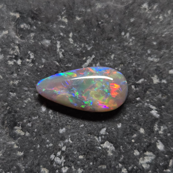 Multicolored opal stone on a dark textured background