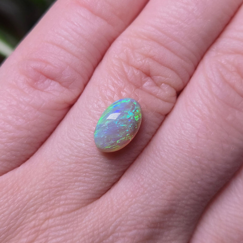 Opal stone on a person's finger with a blurred background