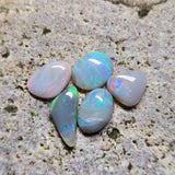 Five opal stones on a textured stone surface