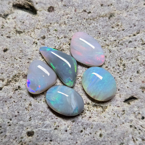 Five opal stones on a textured stone surface