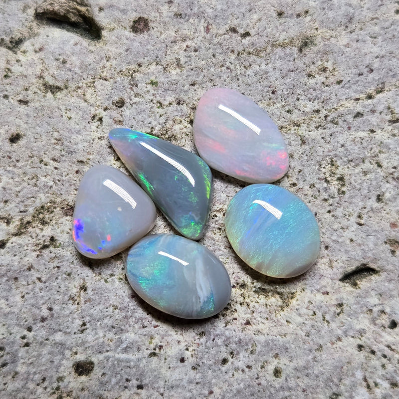Five opal stones on a textured stone surface