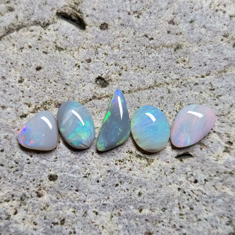 Five opal stones on a textured stone surface