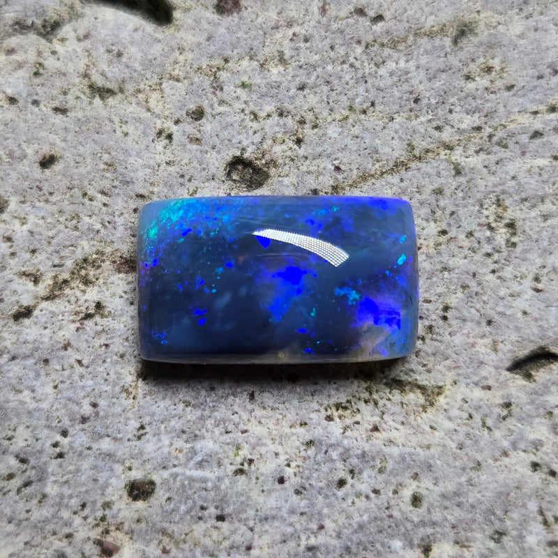 Blue opal stone on a textured gray surface