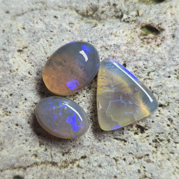Three opal stones on a textured stone surface